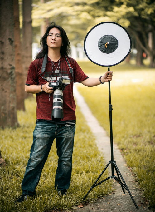woman in red and white plaid shirt and blue denim jeans holding black and white camera